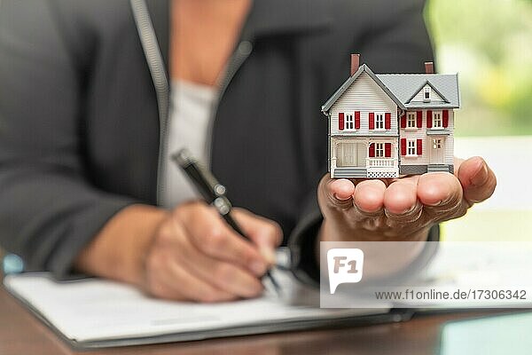 Frau Unterzeichnung Immobilien Vertrag Papiere halten kleine Modell zu Hause vor