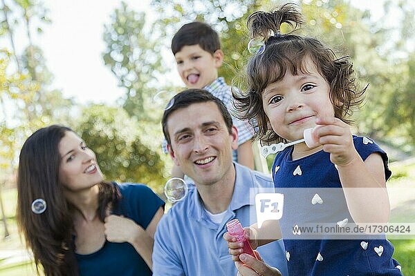 Niedliche junge Baby-Mädchen bläst Blasen mit ihrer Familie im Park