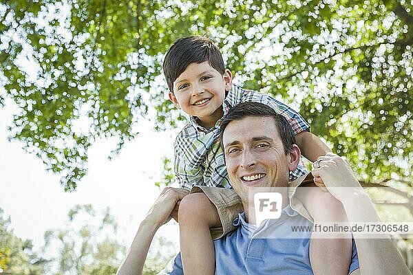 Gemischtrassiger Vater und Sohn spielen zusammen Huckepack im Park