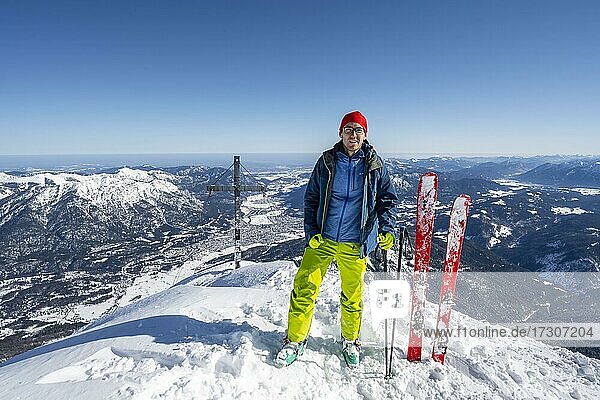 Skitourengeher steht neben seinen Skiern  Skitour auf die Alpspitze  Wettersteingebirge mit Schnee im Winter  Garmisch-Partenkirchen  Bayern  Deutschland  Europa