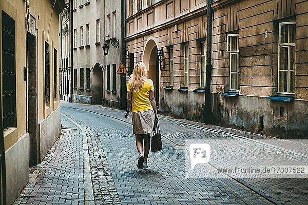 Frau in gelbem T-Shirt  geht zu Fuß durch die alten Straßen von Warschau  Polen  Europa
