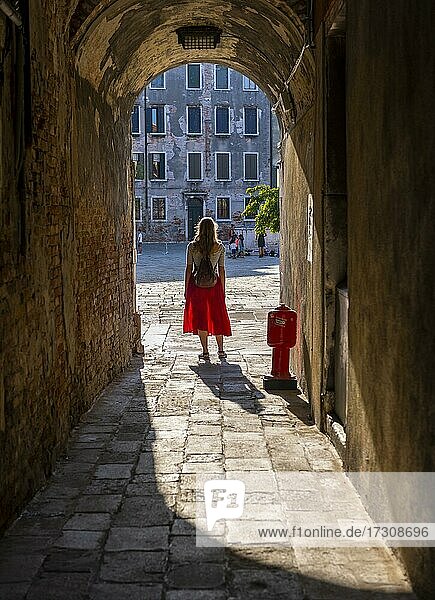 Junge Frau in Rotem Kleid geht durch enge Gasse  Venedig  Venetien  Italien  Europa