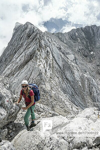 Young female hiker with helmet  rocky mountains and scree  hiking to the Hochkalter  Berchtesgadener Alpen  Berchtesgadener Land  Upper Bavaria  Bavaria  Germany  Europe