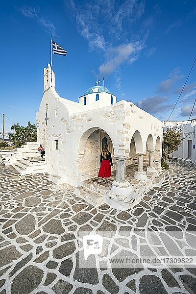 Touristin mit rotem Kleid  Blaue-Weiße Griechisch-Orthodoxe Kirche Agios Nikolaos mit Griechischer Flagge  Parikia  Paros  Kykladen  Ägäis  Griechenland  Europa