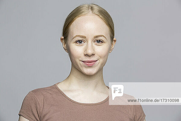 Portrait confident smiling young woman on gray background