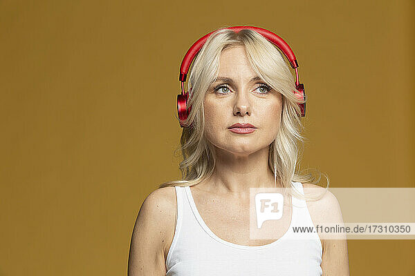 Studio portrait beautiful blonde woman listening to music with headphones