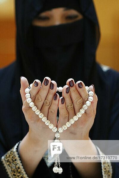 Nahaufnahme der Hände einer muslimischen Frau in Abaya  die einen Rosenkranz hält und betet  Vereinigte Arabische Emirate  Naher Osten