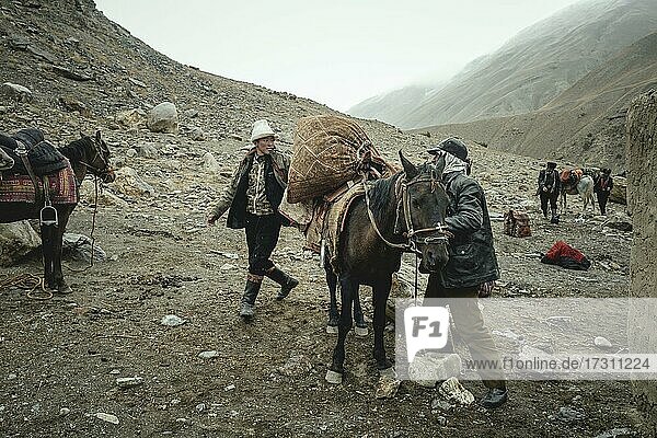 Two men loading a packhorse  Kyrgyz nomads  Wakhan Corridor  Badakhshan  Afghanistan  Asia