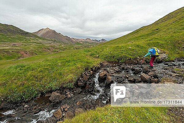 Girl crossing stream  Brúnavík  Víknaslódir  Iceland  Europe