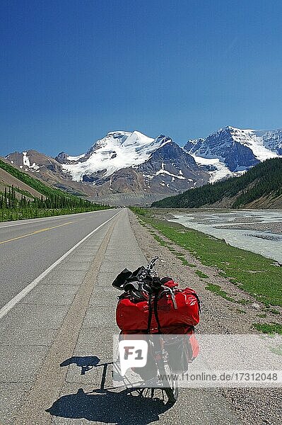 Loaded red touring bike on straight road  high mountains and glaciers in background  Icefields Parkway  Rocky Mountains  Alberta  Canada  North America