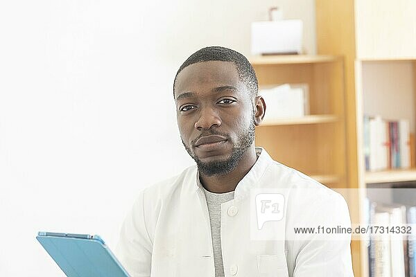 Young black doctor with smock and tablet explaining in the surgery  Freiburg  Baden-Württemberg  Germany  Europe
