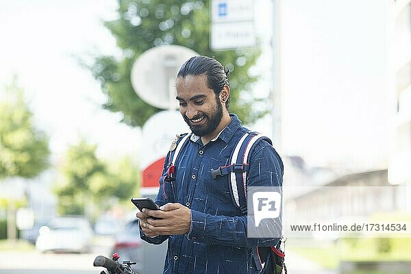 Junger Mann mit Smartphone checkt Leihrad in der Stadt  Freiburg  Baden-Württemberg  Deutschland  Europa