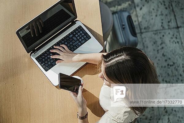 Junge Berufstätige mit Laptop und Mobiltelefon in einem Cafe
