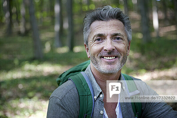 Lächelnder  gut aussehender männlicher Wanderer mit grauem Haar und Stoppeln