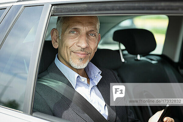 Lächelnder Geschäftsmann auf dem Rücksitz im Auto