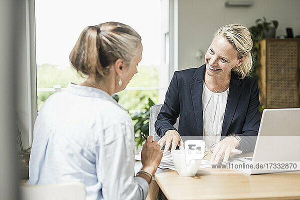 Geschäftsfrau erklärt Kunden  während sie im Büro sitzt
