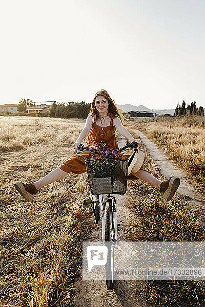 Unbekümmerte rothaarige Frau auf dem Fahrrad in einem Feld
