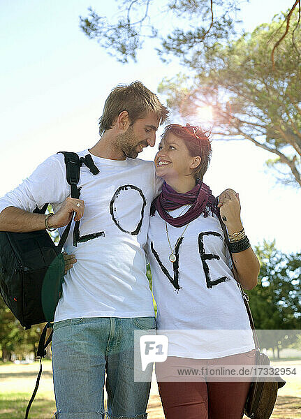 Verliebtes Paar in T-Shirts mit Liebestext  das sich in einem öffentlichen Park ansieht