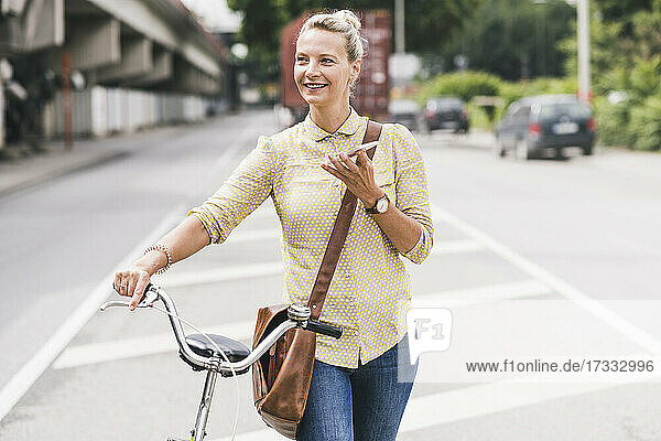 Weibliche Fachkraft  die mit einem Mobiltelefon spricht  während sie Fahrrad fährt