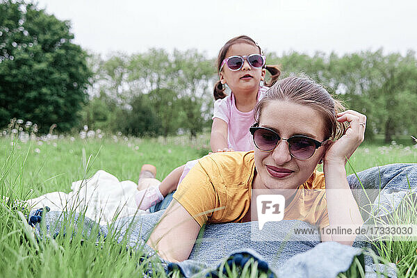Mother and daughter with sunglasses lying on grass in park