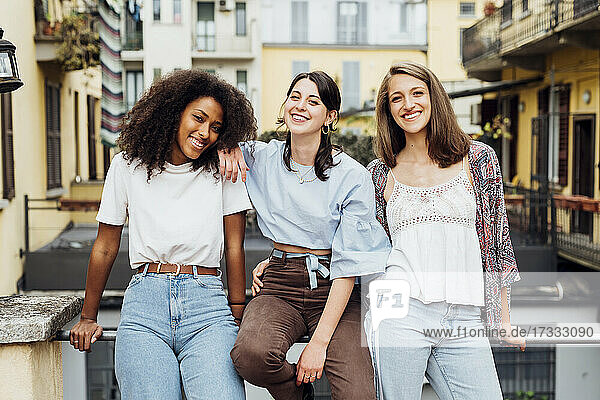 Lächelnde junge Freunde  die an einem Terrassengeländer lehnen