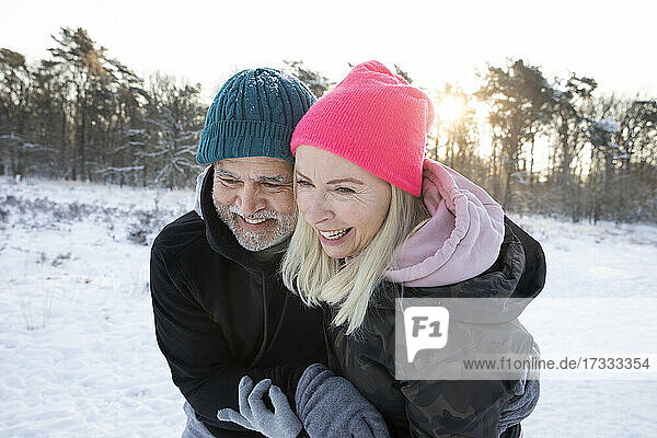 Lächelnder Mann umarmt Frau im Winter