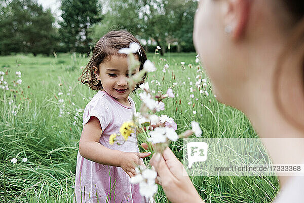 Nettes Mädchen mit Mutter hält Blumen auf Gras im Park