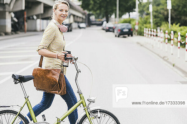 Female commuter wheeling bicycle on street