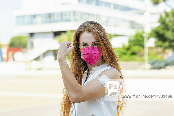 Weibliche Fachkraft mit Gesichtsschutzmaske beim Anspannen der Muskeln während COVID-19