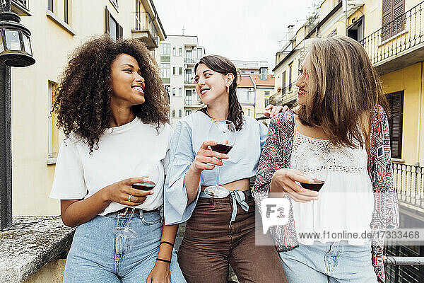 Freunde mit Weingläsern unterhalten sich auf der Terrasse miteinander