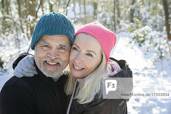 Senior couple with cheek to cheek smiling in forest