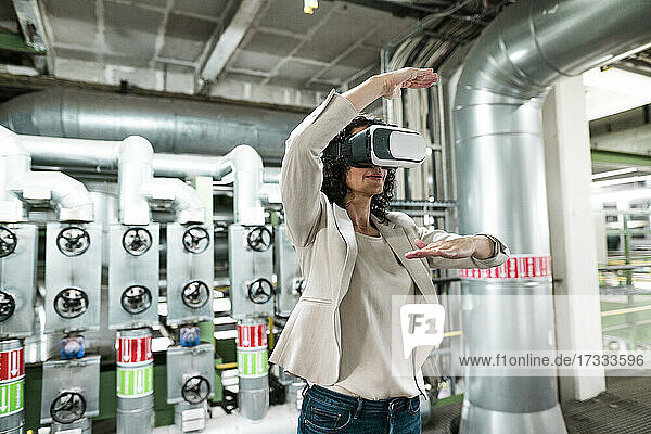 Weiblicher Experte gestikuliert bei der Verwendung eines Virtual-Reality-Headsets in der Industrie