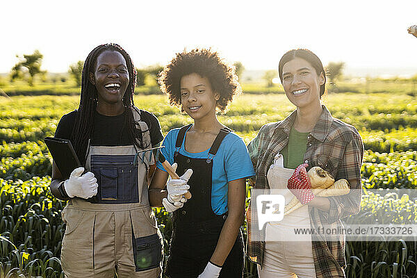 Fröhliche Landarbeiter mit Mädchen  die zusammen auf einem Bauernhof stehen