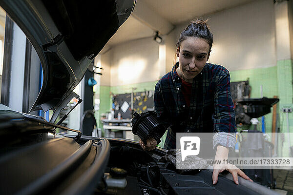 Mechanikerin repariert Auto in der Werkstatt