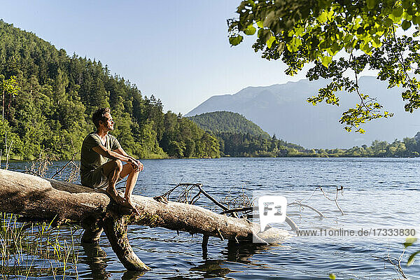 Mann sitzt an einem sonnigen Tag am See