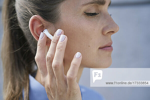 Geschäftsfrau berührt drahtlose In-Ear-Kopfhörer