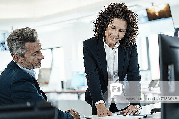 Geschäftsfrau beim Lesen eines Dokuments  während sie mit einem Kollegen am Hauptsitz arbeitet