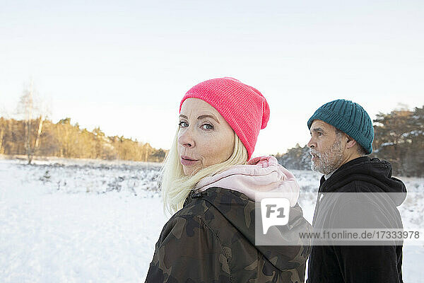 Woman looking over shoulder while standing by man during winter