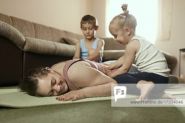 Sohn und Tochter massieren den Rücken der Mutter auf einer Übungsmatte zu Hause