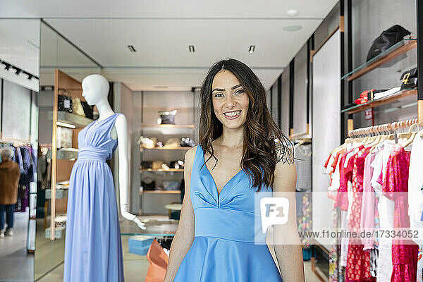 Beautiful woman smiling while wearing blue dress in boutique