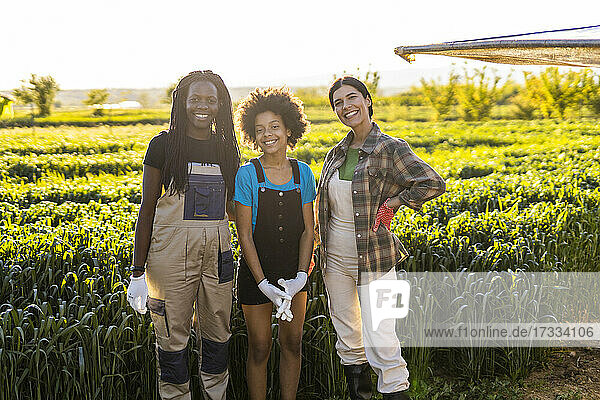 Lächelnde Bäuerinnen mit Mädchen auf einem Bio-Bauernhof an einem sonnigen Tag