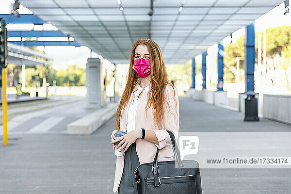 Geschäftsfrau mit Gesichtsschutzmaske auf dem Bahnsteig