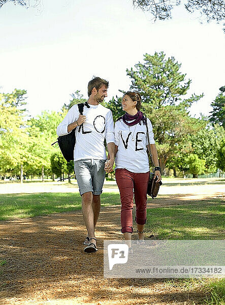 Junges Paar hält sich beim Spaziergang im öffentlichen Park an den Händen