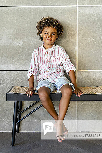 Cute boy smiling while sitting on bench