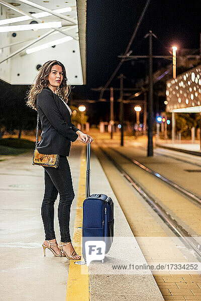 Geschäftsfrau mit Gepäck wartet oder Straßenbahn in der Nacht