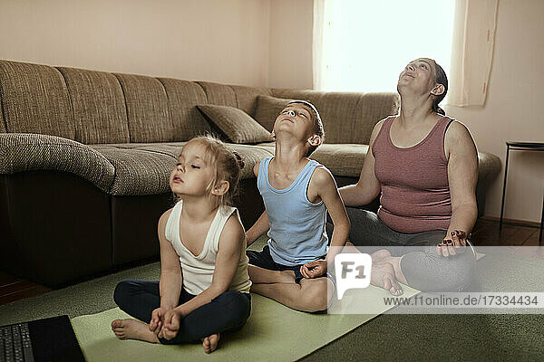 Sohn und Tochter üben Yoga mit der Mutter zu Hause