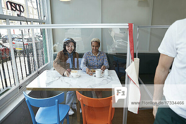 Lesbisches Paar sitzt zusammen am Tisch in einem Café  gesehen durch Glas