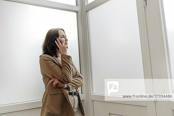 Junge Frau  die im Büro mit einem Smartphone telefoniert