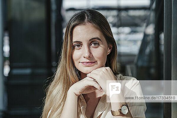 Schöne junge Frau sitzt mit Händen auf dem Kinn in einem Cafe