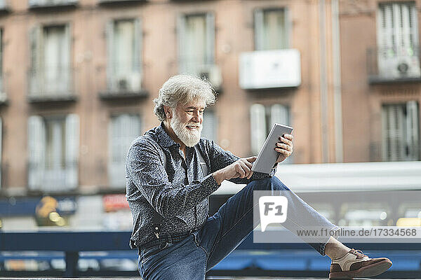 Smiling mature man using digital tablet in city